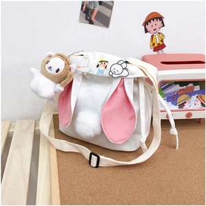 Detail of canvas bucket bag featuring cute pink rabbit ears and fluffy white pom-pom tail