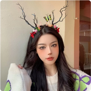 Detail view of a reindeer antler headband featuring dark branches, berries and a butterfly