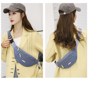 Blue nylon crossbody waist bag with multi-zipper layers and adjustable strap shown on model