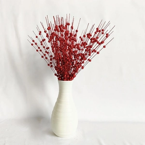 Glittery red berry stems for Christmas tree decoration in a white textured vase