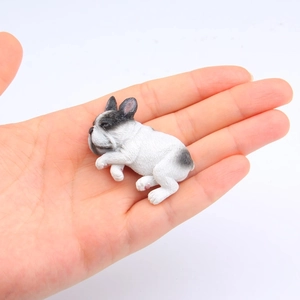 Miniature sleeping French Bulldog model in palm showing realistic black and white details