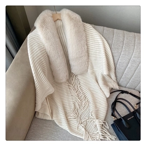 Close-up of knit poncho featuring premium faux fur collar and elegant fringe details