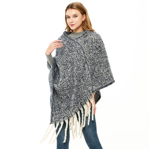 Detailed view of the thick knit texture and cream fringe tassels on a checkered poncho