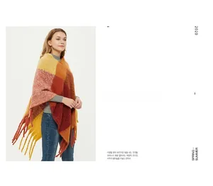 Detail of chunky knit shawl with vibrant orange and yellow plaid pattern and long tassels