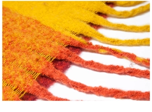 Macro shot of yellow and orange plaid knit fabric texture with thick fringe details