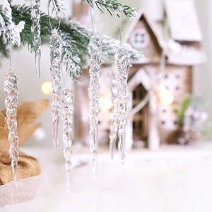 Transparent twisted icicle ornaments hanging on snowy pine branches with warm festive lights