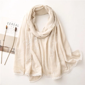 Detail of beige cotton linen scarf featuring exquisite floral embroidery and lace trim