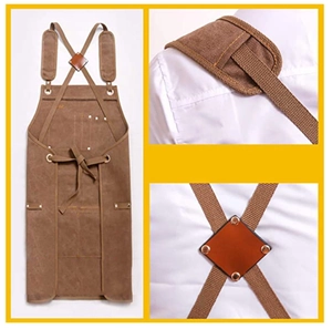 Detail of brown canvas apron featuring cross-back leather straps and metal hardware