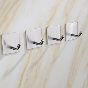 Detail of four brushed stainless steel wall hooks installed on light marble texture wall