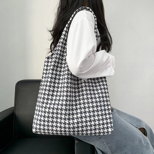 Detail of minimalist houndstooth canvas tote bag displayed on a black leather sofa