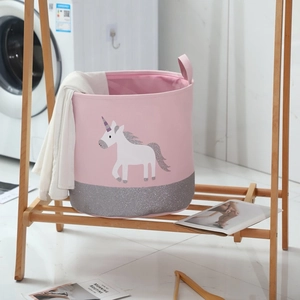 Pink unicorn fabric laundry basket with silver sequins on a wooden shelf in a laundry room