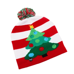 Detail of knitted Christmas hat with LED power switch and green festive tree pattern