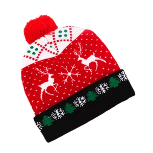 Detail of knitted Christmas hat with colorful reindeer patterns and red pompom top
