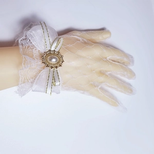 Close-up of white lace Lolita glove with satin bow and pearl brooch detail