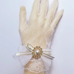 Close-up of white lace Lolita glove featuring a sheer bow, pearl and rhinestone charm