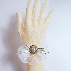 Detailed view of white lace gloves with ribbon bow, faux pearl, and rhinestone accents