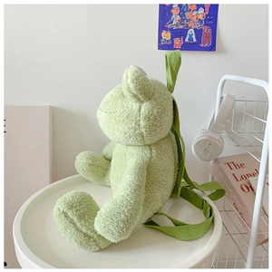 Detailed close-up of a cute green plush frog backpack on a minimalist white table