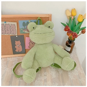 Detail of green plush frog backpack showing soft texture and woven shoulder straps