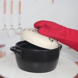 Silicone heat resistant glove lifting a ceramic pot lid in a modern kitchen setting