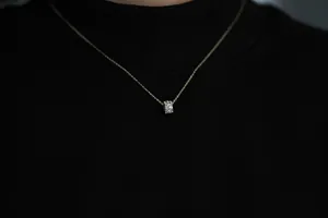Detail of 14K gold plated silver necklace with a cylinder pendant on black sweater