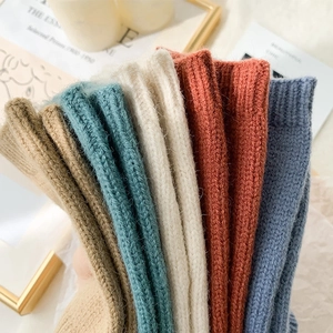Close-up of six pairs of thick ribbed knit fingerless gloves in various earthy colors
