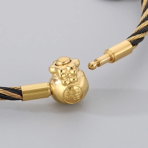 Macro shot of 3mm braided wire bracelet with lucky gold money bag clasp and Fu character