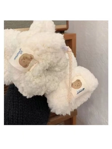 Close-up of white plush lamb wool gloves featuring a cute brown bear patch and hanging cord