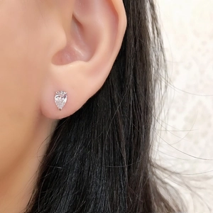 Close-up of a pear-cut white zircon stud earring in silver on a woman's earlobe