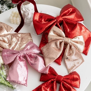 Pink and gold sequin Christmas tree bow ornaments on a decorative white table