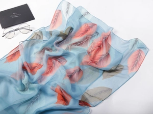 Detail of light blue chiffon scarf showing multi-color leaf print and sheer texture