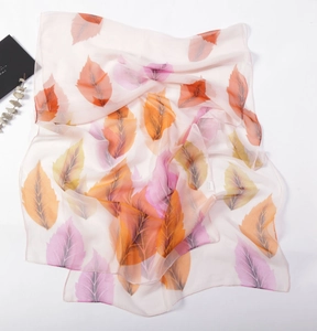 Macro detail of translucent chiffon scarf with autumn leaf patterns on white surface