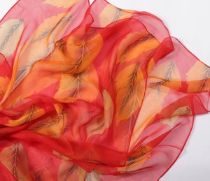 Detail of red chiffon scarf showing vibrant gradient leaf patterns and soft silky texture