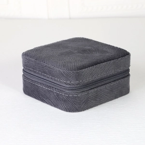 Top view of a square dark grey velvet jewelry box with a textured finish and metal zipper