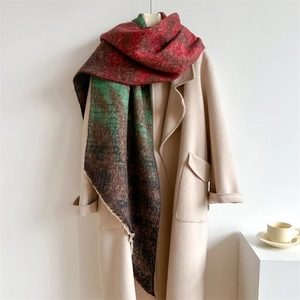Détail d'une écharpe à carreaux rouge et vert avec franges sur un manteau beige
