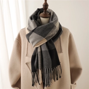 Detailed texture of black and white plaid cashmere blend scarf on a beige coat