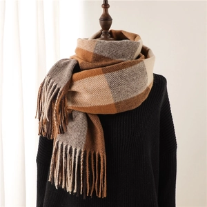 Detail of thick plaid scarf with soft tassels in brown and beige patterns