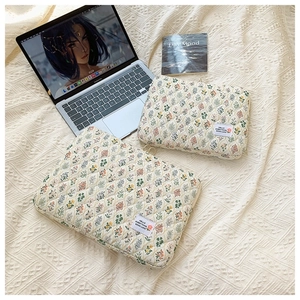 Close-up of floral quilted laptop sleeve showing soft fabric texture and fabric label
