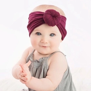 Close-up of a burgundy baby headband with a decorative doughnut knot on a white background