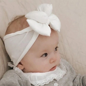 Close-up of baby girl wearing a white soft fabric headband with a large knot bow