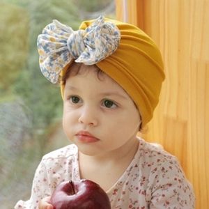 Close-up of ginger yellow baby turban hat with a floral bow on a cute infant