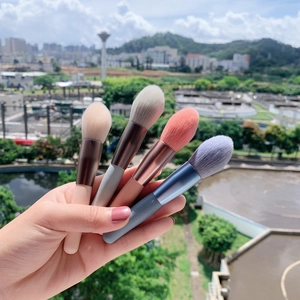 Detail of 4 soft mini makeup brushes in pastel colors held by hand for easy travel