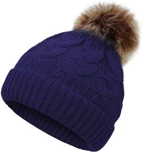 Close-up of navy blue cable knit hat with a large brown faux fur pompom detail