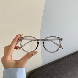 Occhiali con montatura rotonda grigio trasparente con filtro luce blu e dettagli dorati