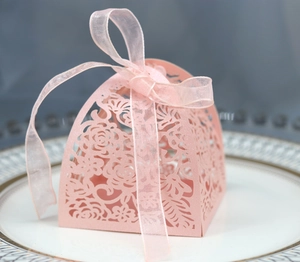 Macro shot of pink laser-cut rose hollow favor box with elegant organza ribbon bow