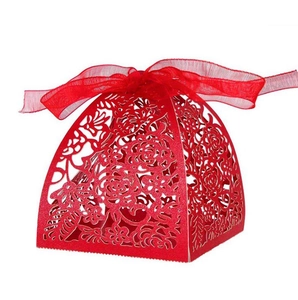 Close-up of red laser-cut wedding favor box with rose patterns and ribbon bow tie