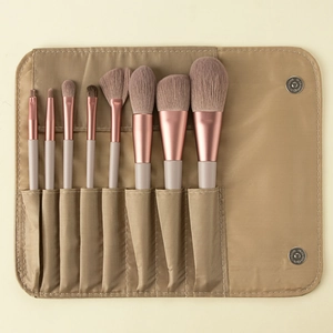 Detailed view of 8 professional makeup brushes with a khaki fabric roll-up storage case