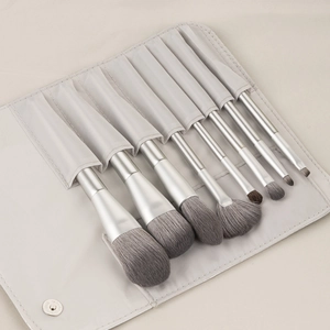 Detailed set of 8 makeup brushes with grey bristles and silver handles in a beige pouch