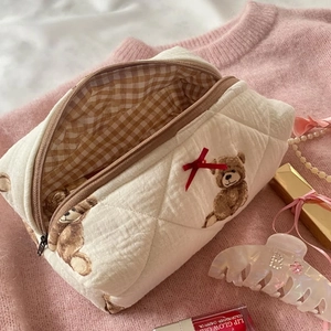 Quilted teddy bear makeup bag with brown check lining and red bow detail in soft pink setting