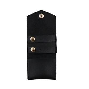 Portable black lychee textured leather jewelry organizer with golden snaps on white background