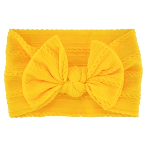Close-up of yellow soft knitted baby headband with a large bow and ribbed texture